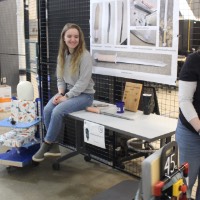 Two students looking at a child sized wheelchair.